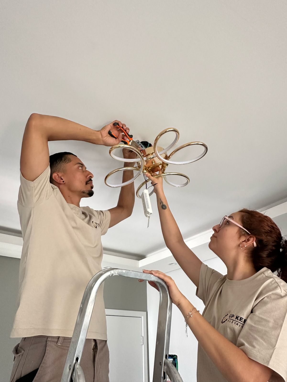 Dois eletricistas da Up Keep instalando uma luminária no teto de uma residência